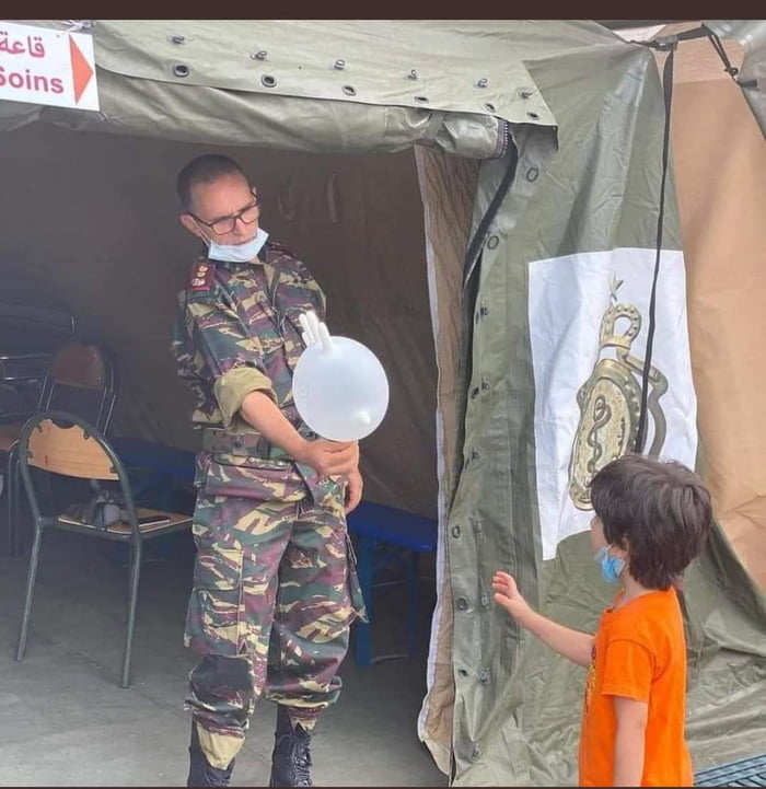 A Morrocan soldier in a field hospital gives a balloon made of a glove to a Lebanese kid