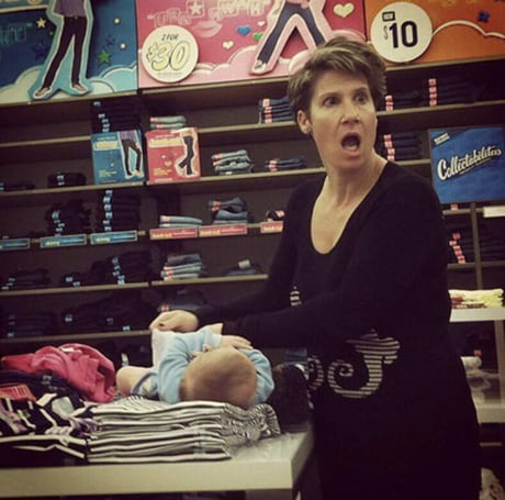 "Taking a picture of me???" - Woman changing her baby's dirty diaper on top of an Old Navy clothing display